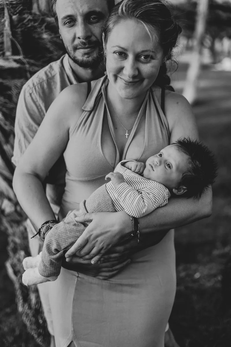 Black and white portrait of happy parents with newborn during outdoor newborn photography session Tenerife smiling