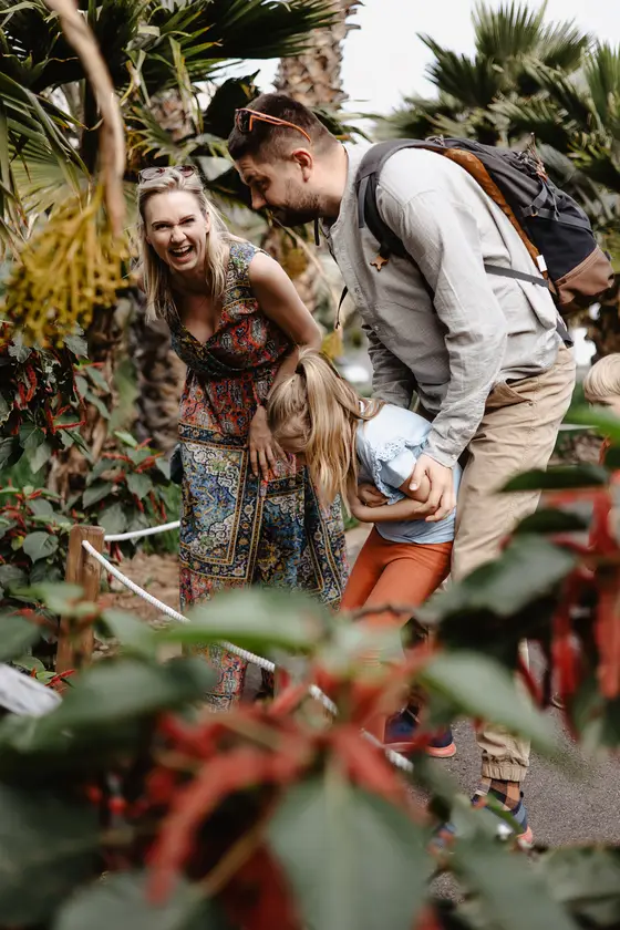 Familia riéndose y jugando entre palmeras tropicales en el Jardín Botánico Palmetum