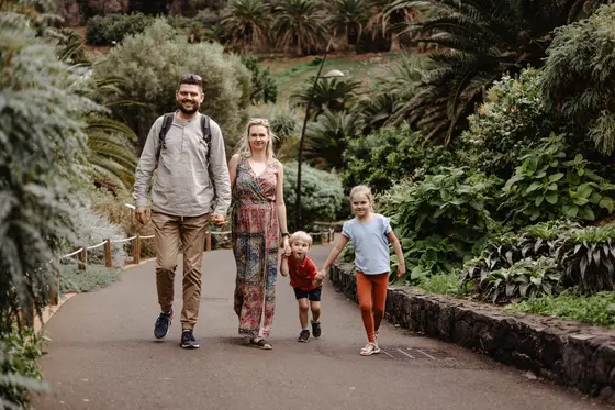 Cuatro miembros de la familia caminando juntos por senderos botánicos en el Palmetum Tenerife