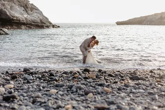 Wedding couple in romantic kiss on black pebble volcanic beach at Playa Paraiso