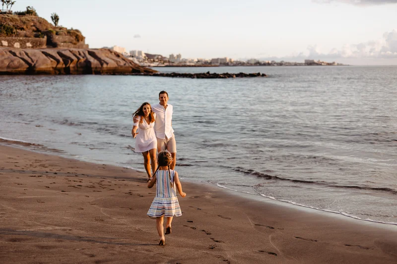 Little girl playing on beach during golden hour with waves in background