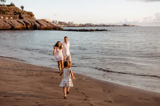 Little girl playing on beach during golden hour with waves in background