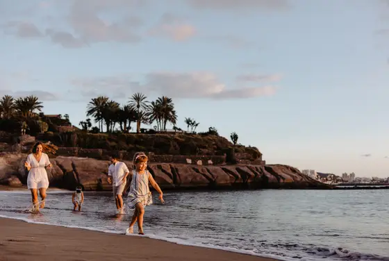 Family with children walking on beach during golden hour in Tenerife wearing summer outfits