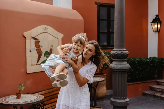 Mother with child laughing in front of Spanish villa with colorful tiles and plants