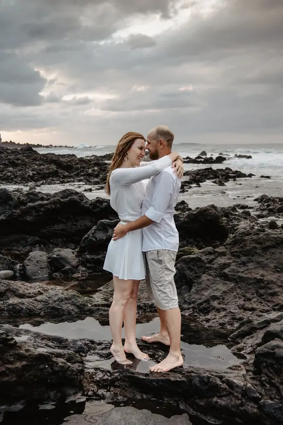 Couple walking on beach with Puerto de la Cruz buildings background