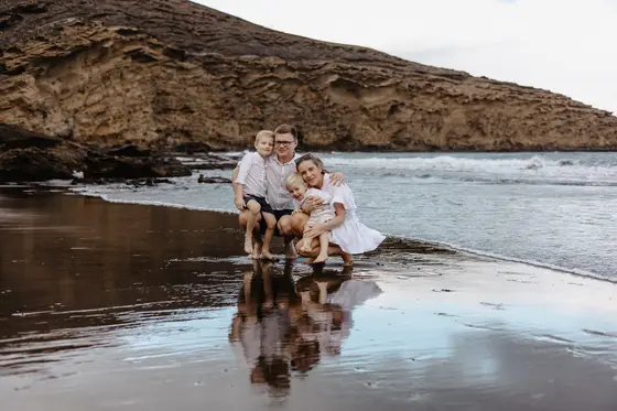 Family adventure on Tenerife volcanic beach with water reflection and rocky landscape backdrop