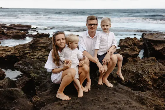 Family session on Tenerife volcanic rocks with parents and children against ocean backdrop