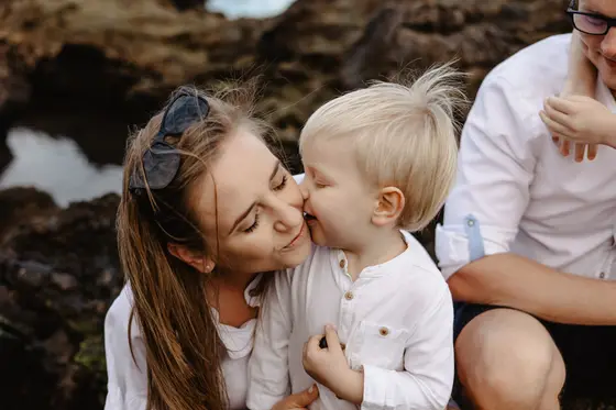 Maternal tenderness during family session on Tenerife volcanic rocks with ocean background