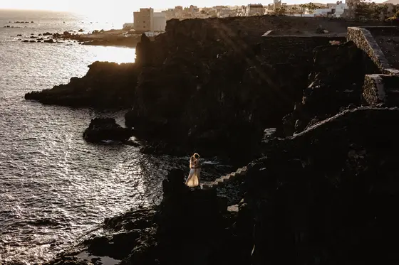 Pareja romántica en costa rocosa de Tenerife durante hora dorada con vistas oceánicas