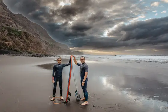 Pareja de surfistas con tablas en playa negra Socorro durante fotografía familiar Tenerife sesión lifestyle