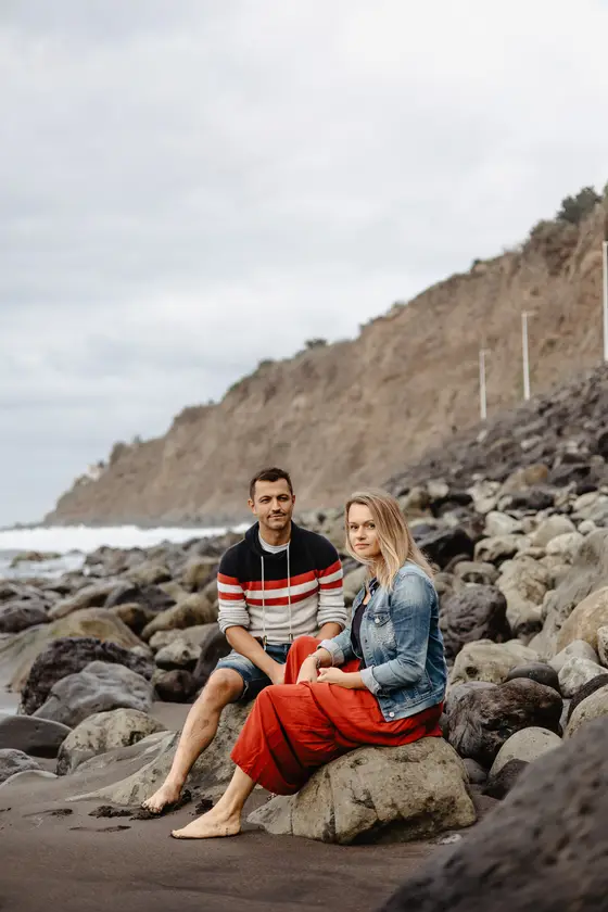 Pareja romántica sentada en rocas volcánicas playa Socorro Tenerife durante sesión fotografía familiar íntima lifestyle