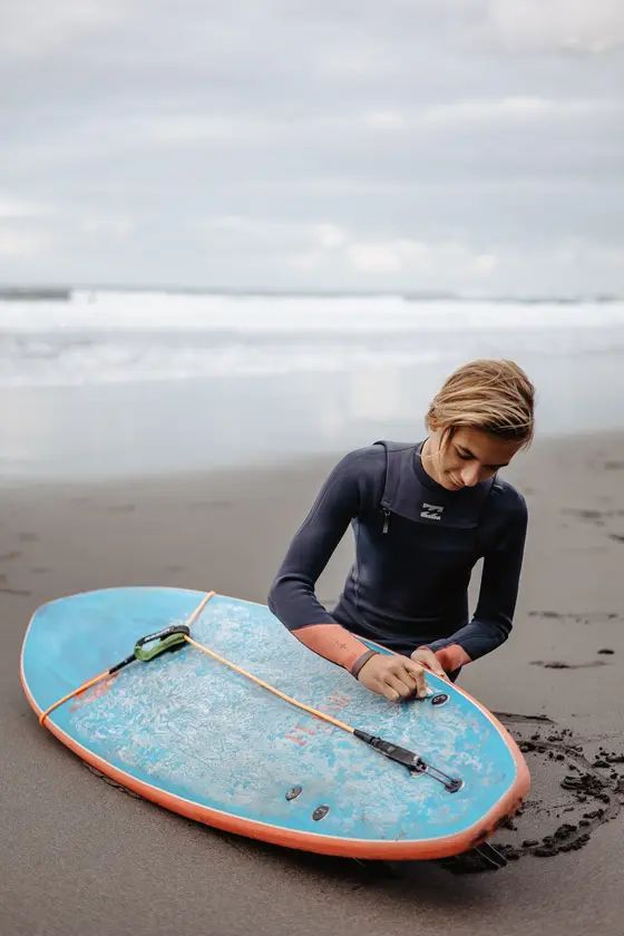 Mujer joven preparando tabla de surf en playa negra Socorro durante sesión fotografía familiar activa Tenerife