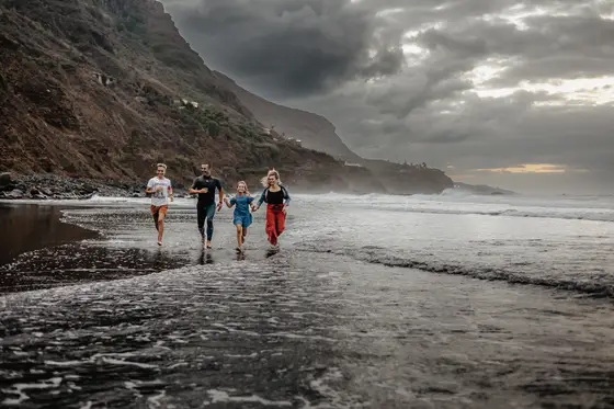 Familia corriendo en arena negra playa Socorro Tenerife durante sesión fotografía familiar dinámica lifestyle fotógrafo