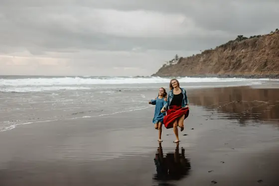 Madre e hija corriendo juntas playa Socorro Tenerife durante sesión fotografía familiar alegre lifestyle