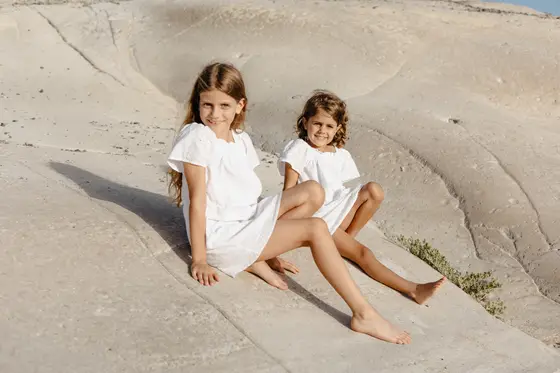 Children sitting on bright volcanic rocks during family photo session in South Tenerife