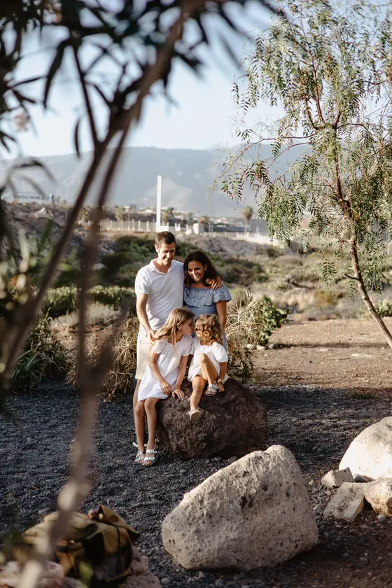 Couple with child in natural South Tenerife setting among volcanic rocks and subtropical vegetation