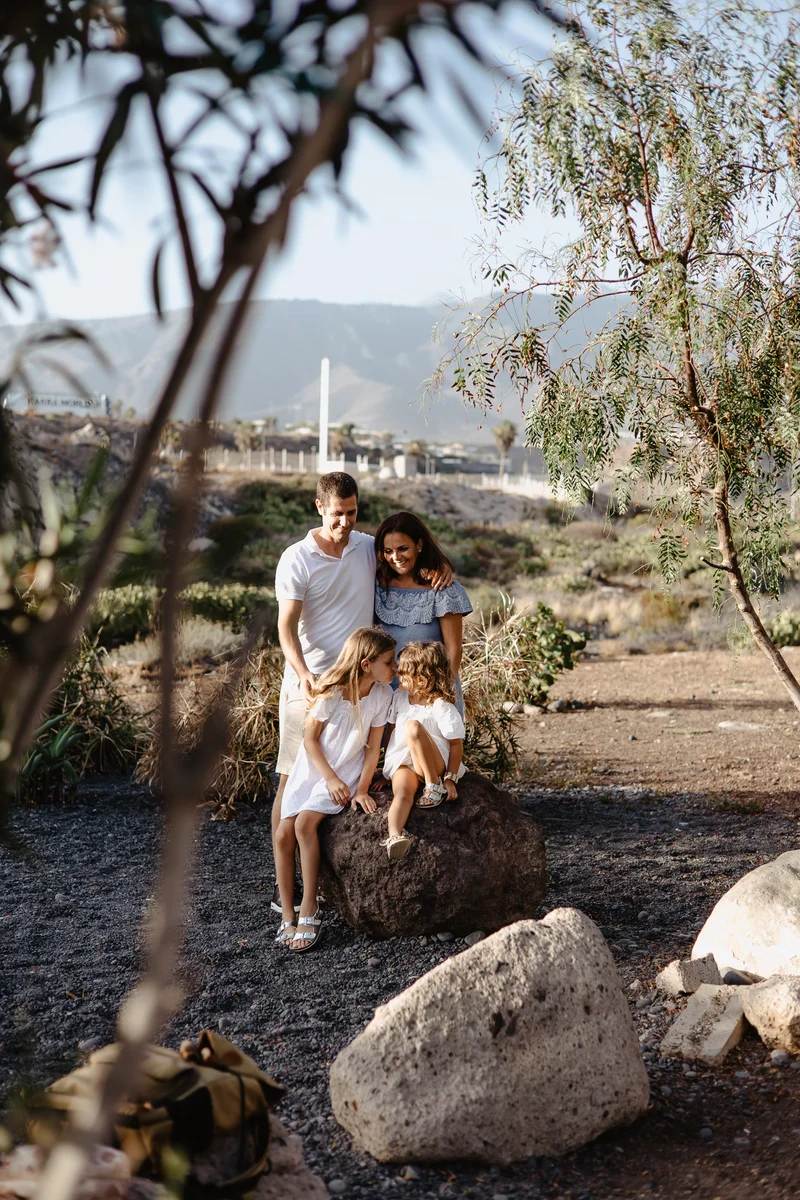 Couple with child in natural South Tenerife setting among volcanic rocks and subtropical vegetation