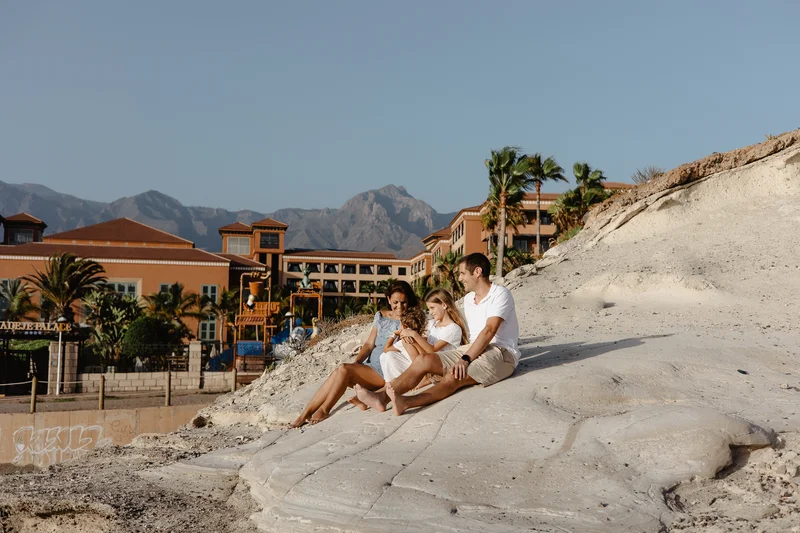 Family with children in white outfits against South Tenerife hotels and mountains during golden hour