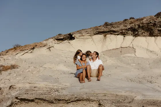 Family embracing on white volcanic cliffs under clear skies of South Tenerife