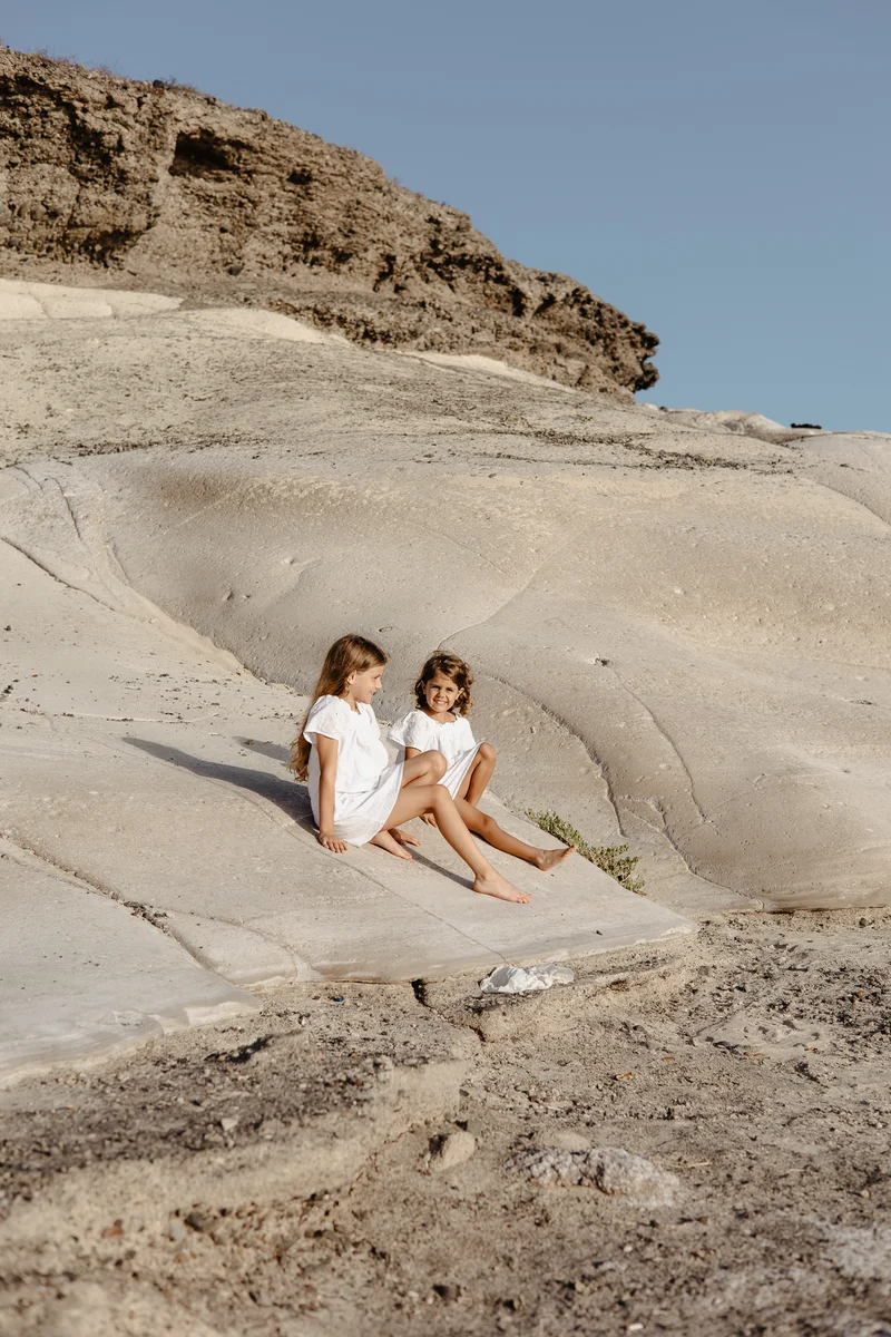Sisters in white clothing relaxing on smooth volcanic surfaces of South Tenerife