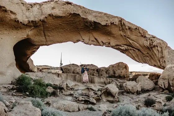 Arco de piedra natural en Tenerife con pareja posando bajo formación rocosa durante hora dorada