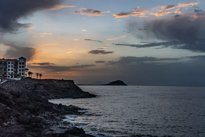 Piscinas naturales en las rocas volcánicas de Tenerife con modelos durante la cálida iluminación del amanecer o atardecer