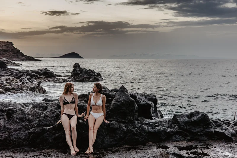 Dos modelos en bikini posando en las rocas volcánicas de Tenerife con vista al océano Atlántico