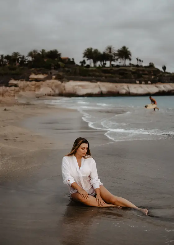 Maternity photoshoot on Tenerife beach - woman in white shirt against ocean backdrop