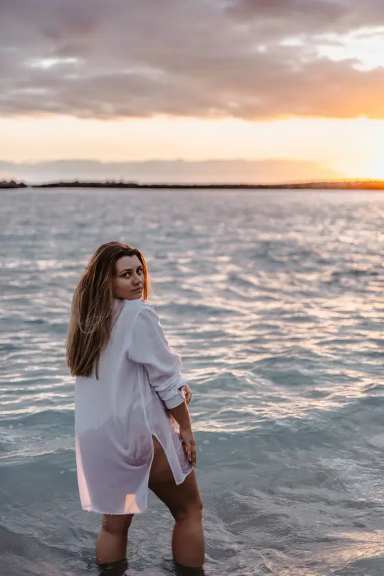 Maternity session in ocean at sunset - woman looking over shoulder