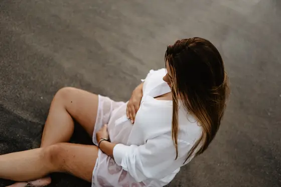 Pregnant woman lying on side on sand embracing pregnancy belly