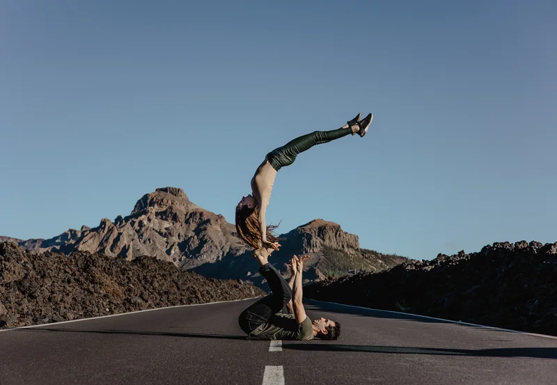Fotografía parejas Teide mujer en pose acrobática en carretera con panorama picos volcánicos
