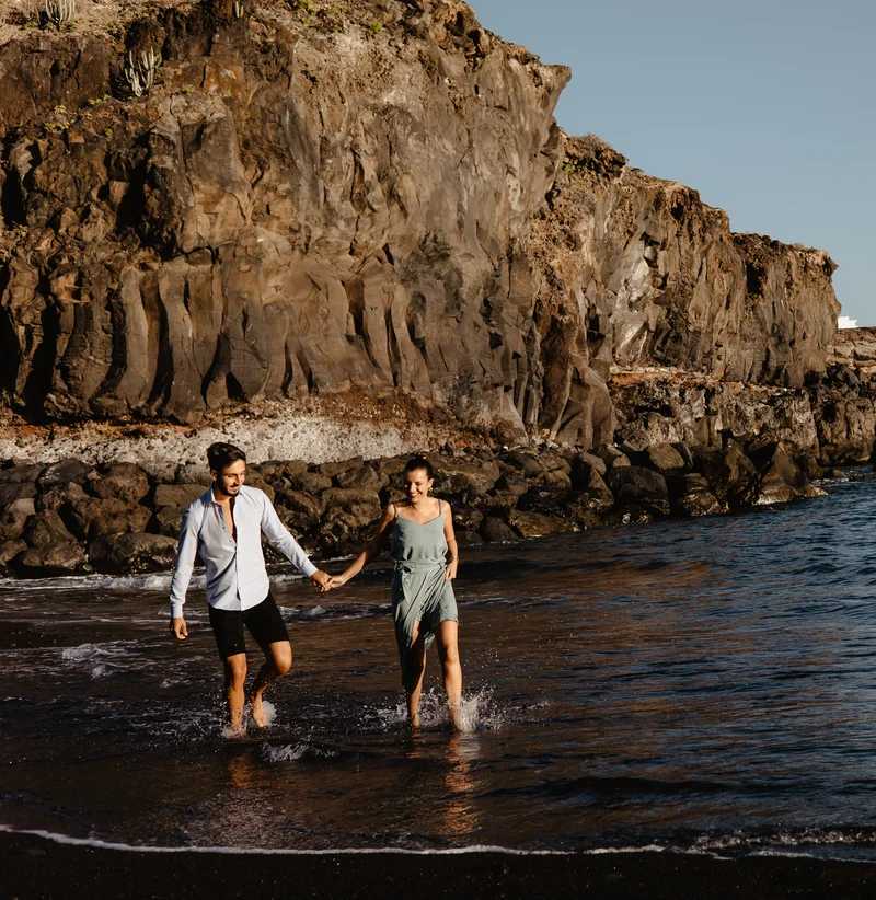 Pareja romántica española contra espectaculares acantilados volcánicos de Tenerife durante sesión fotográfica