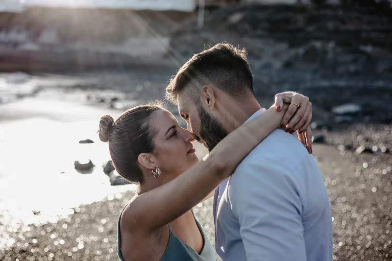 Momento íntimo de pareja española en playa de Tenerife con cálida luz solar