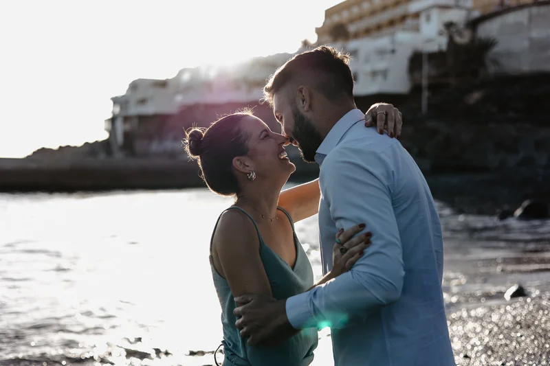 Beso romántico de pareja española con casas coloridas y océano de Tenerife de fondo