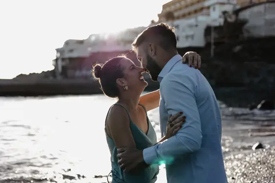Romantic kiss of Spanish couple with colorful houses and Tenerife ocean backdrop