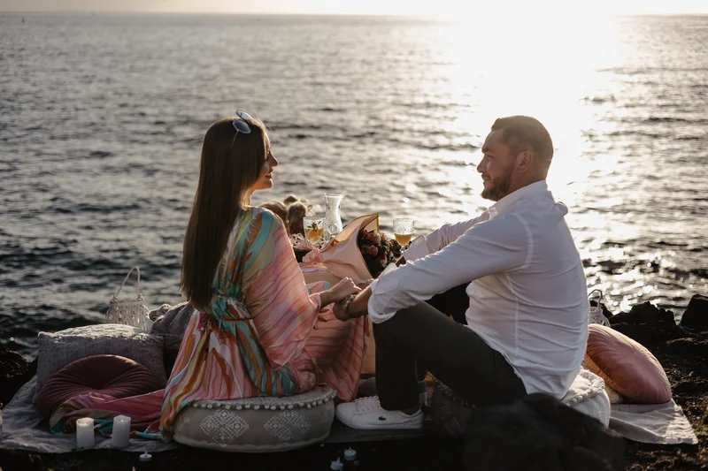 Romantyczny toast szampanem podczas piknikowego oświadczyn na plaży Teneryfa w złotym świetle