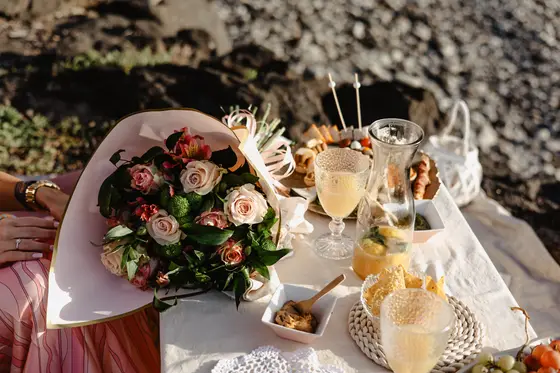 Mesa de picnic elegante con ramo de rosas y champán durante sesión fotográfica de compromiso Tenerife