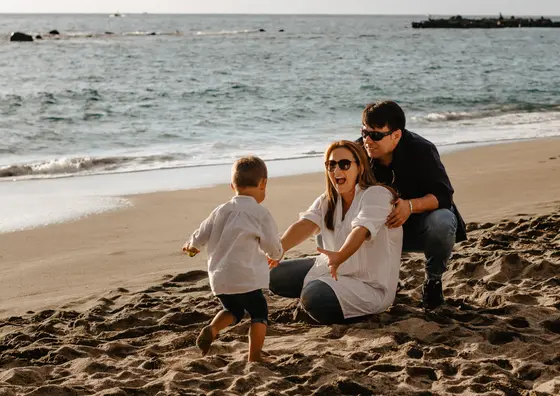 Family sitting on sandy beach during family photography Tenerife coastal session