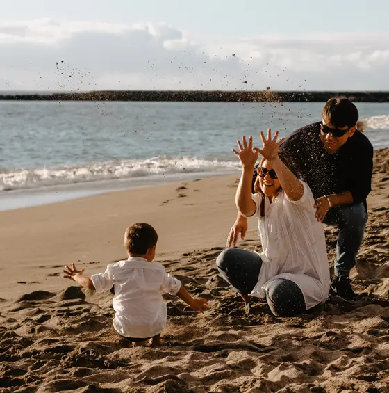 Family playing throwing sand on beach during family photography Tenerife playful session