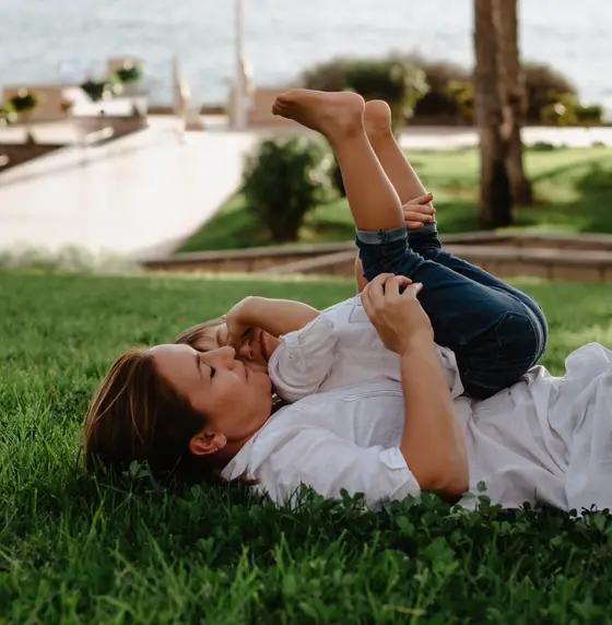 Mother holding child in air on grass during family photography Tenerife playful session
