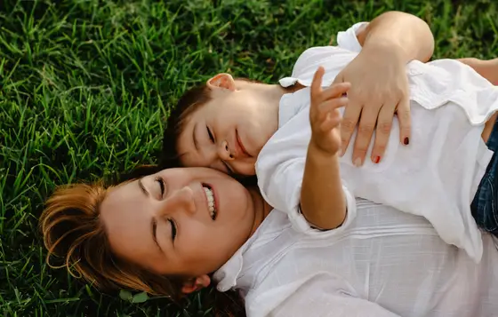 Mother and child lying on grass smiling during family photography Tenerife intimate session