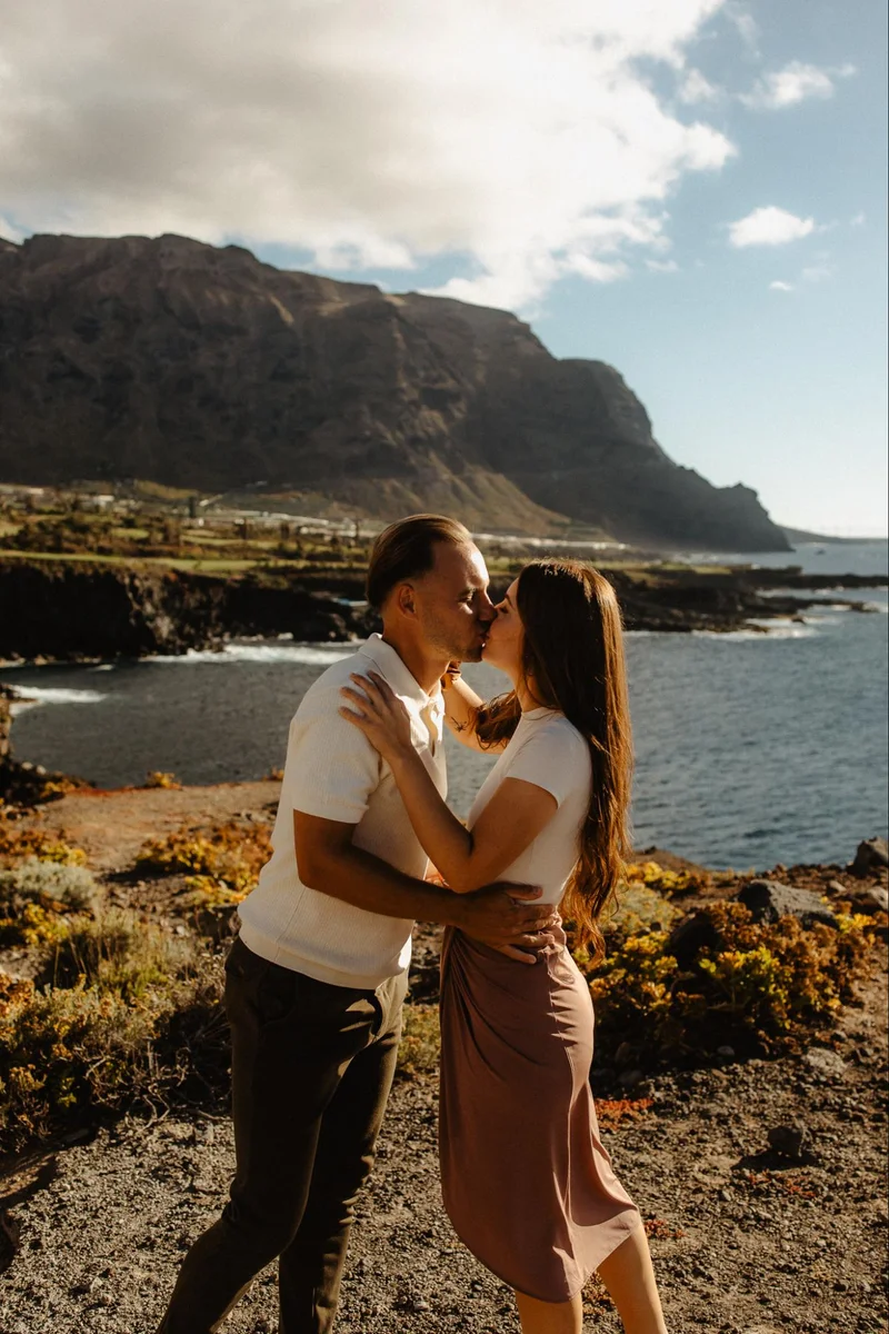 Pareja recién comprometida en Tenerife abrazándose con acantilados, océano y paisaje volcánico