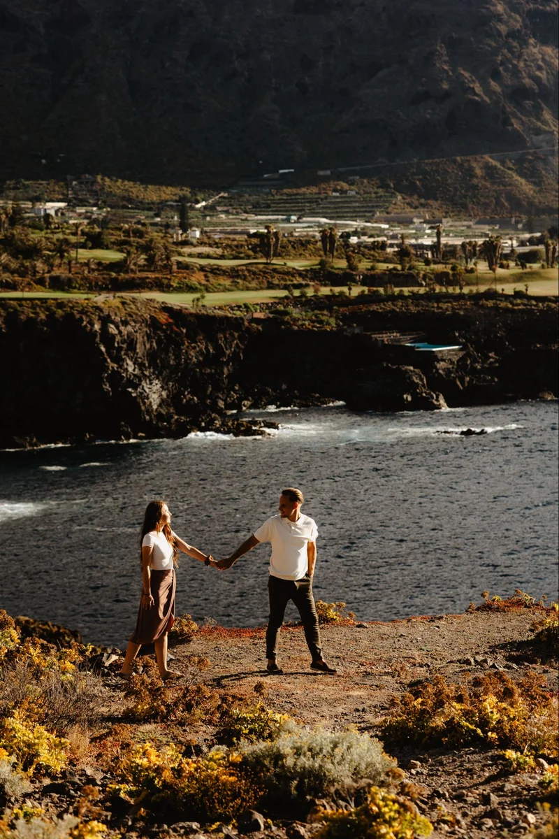 Pareja caminando por la costa rocosa durante una sesión de compromiso