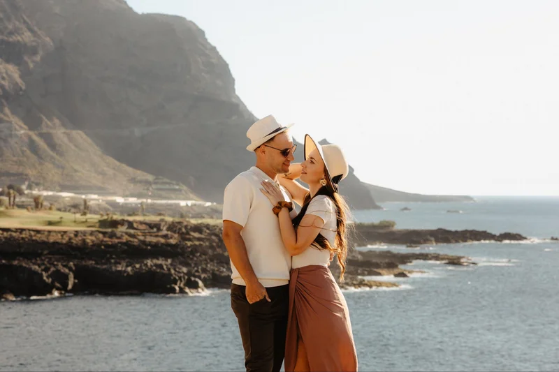 Retrato horizontal de pareja comprometida con océano y acantilados de Tenerife al fondo