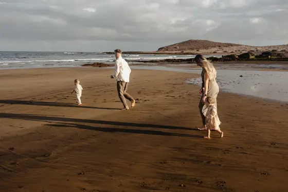 Family running on beach Tenerife family session vacation active recreation mountains background