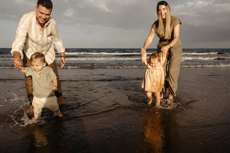Familia jugando en agua océano Tenerife sesión familiar vacaciones alegría niños playa
