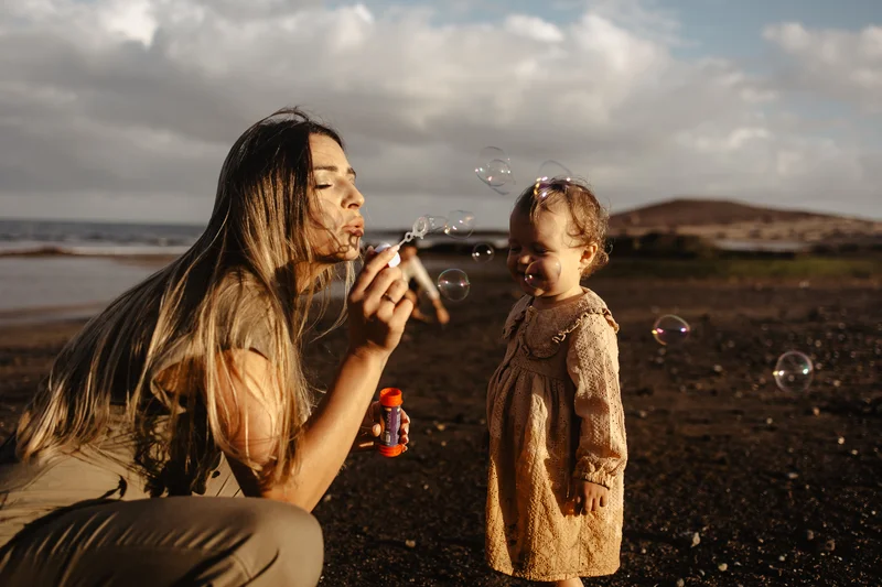 Madre haciendo pompas jabón con hija Tenerife sesión familiar vacaciones momentos alegres playa