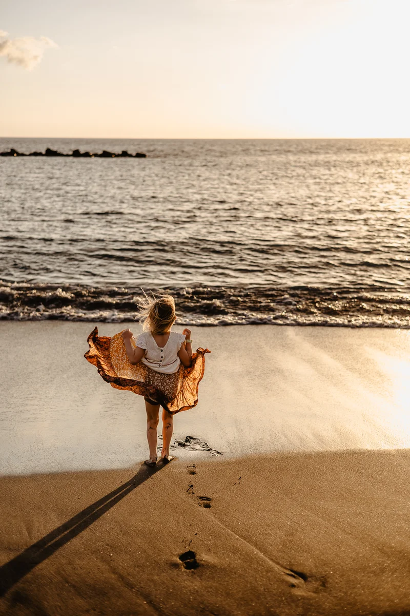 Woman dancing on beach during sunset in natural lifestyle photography session