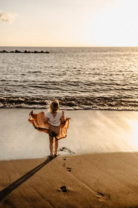 Woman dancing on beach during sunset in natural lifestyle photography session