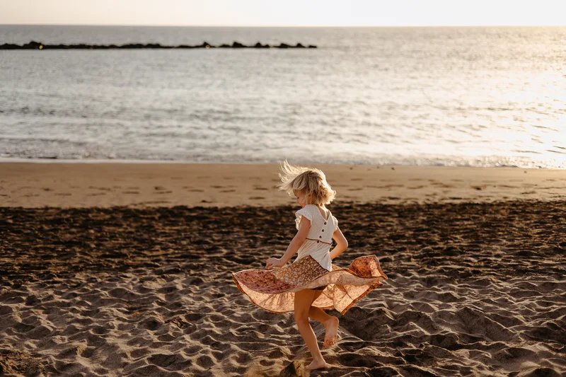 Little girl in flowing dress during beach play in lifestyle photography style